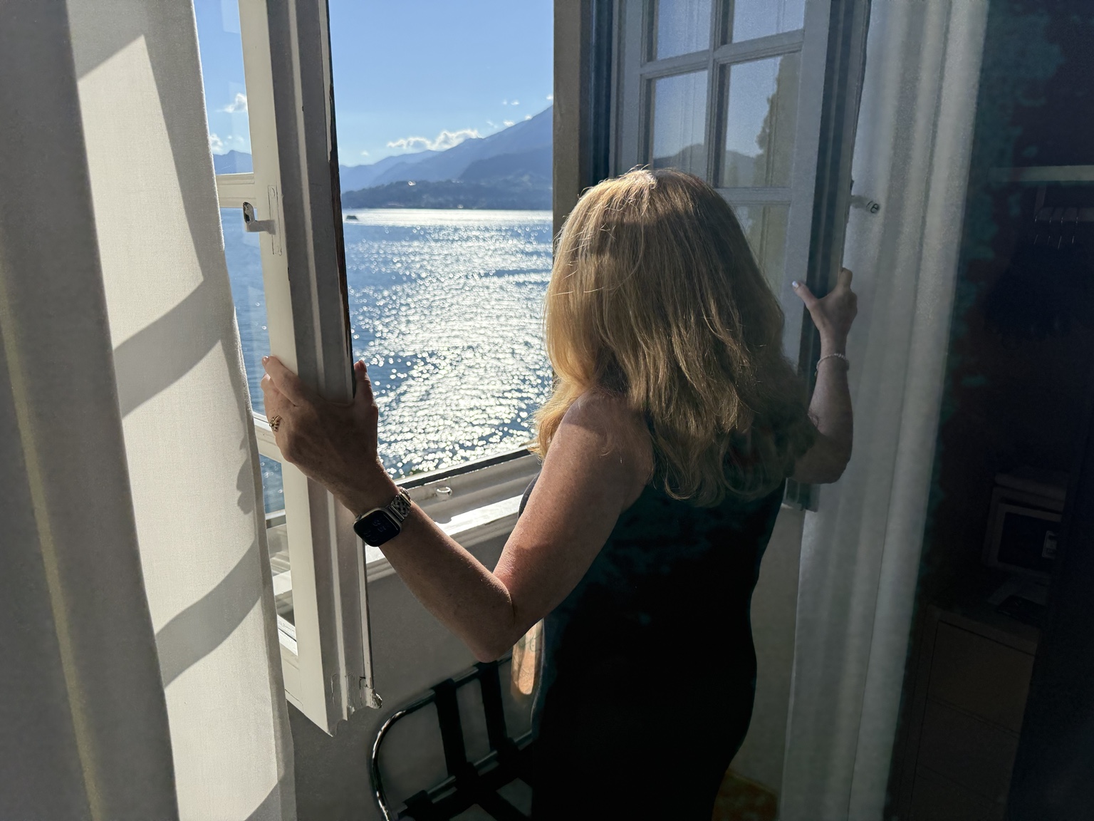 Angie opening a window overlooking Lake Como